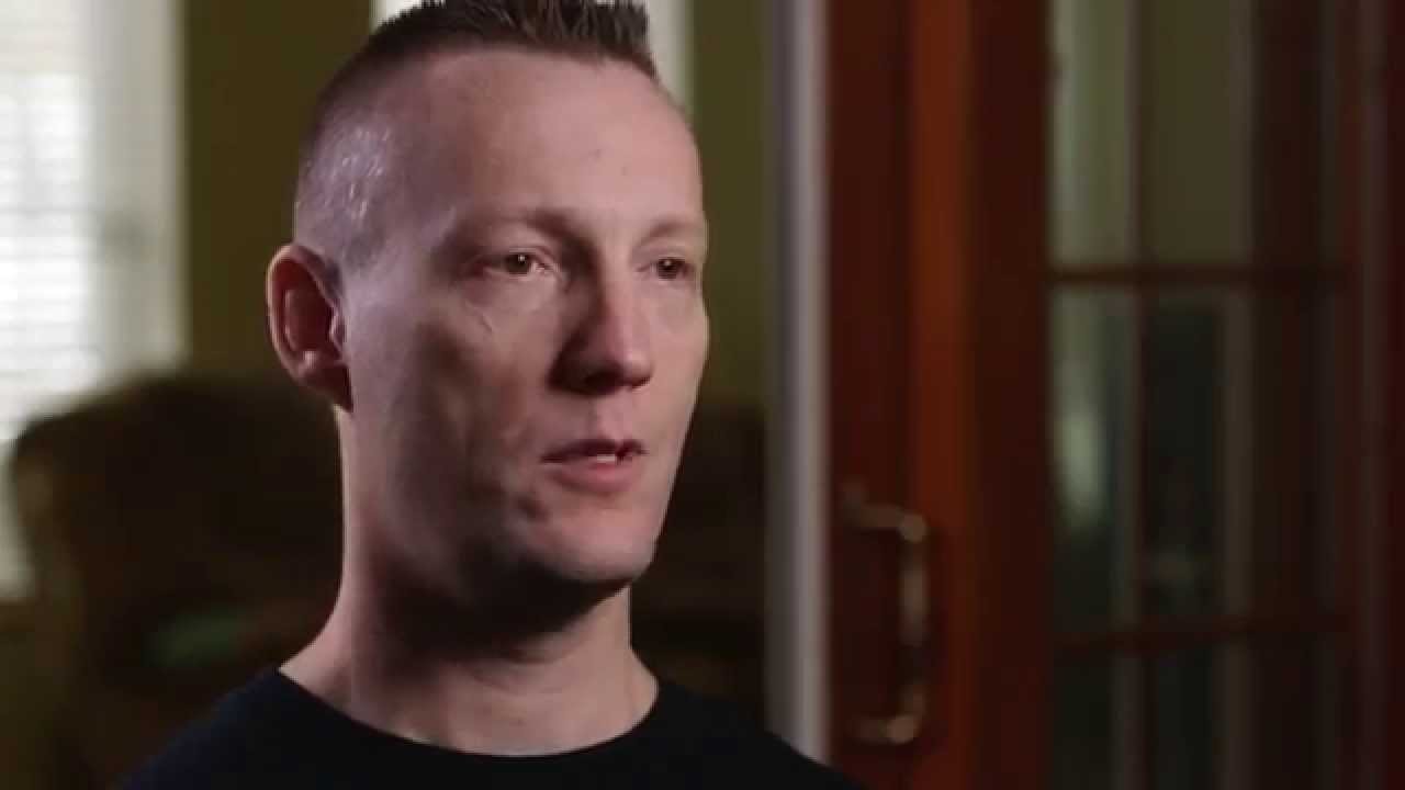 Close-up of a person in a dark shirt looking to the right indoors.